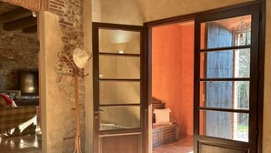 A room with a large wooden door, a stone wall, a floor lamp, and a view of the outdoors. - Costabravapartment Can Marc with private pool and tennis court (Massanes (Girona))