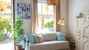 A cozy room with a striped sofa, a potted plant, a lamp, and a cabinet with drawers.