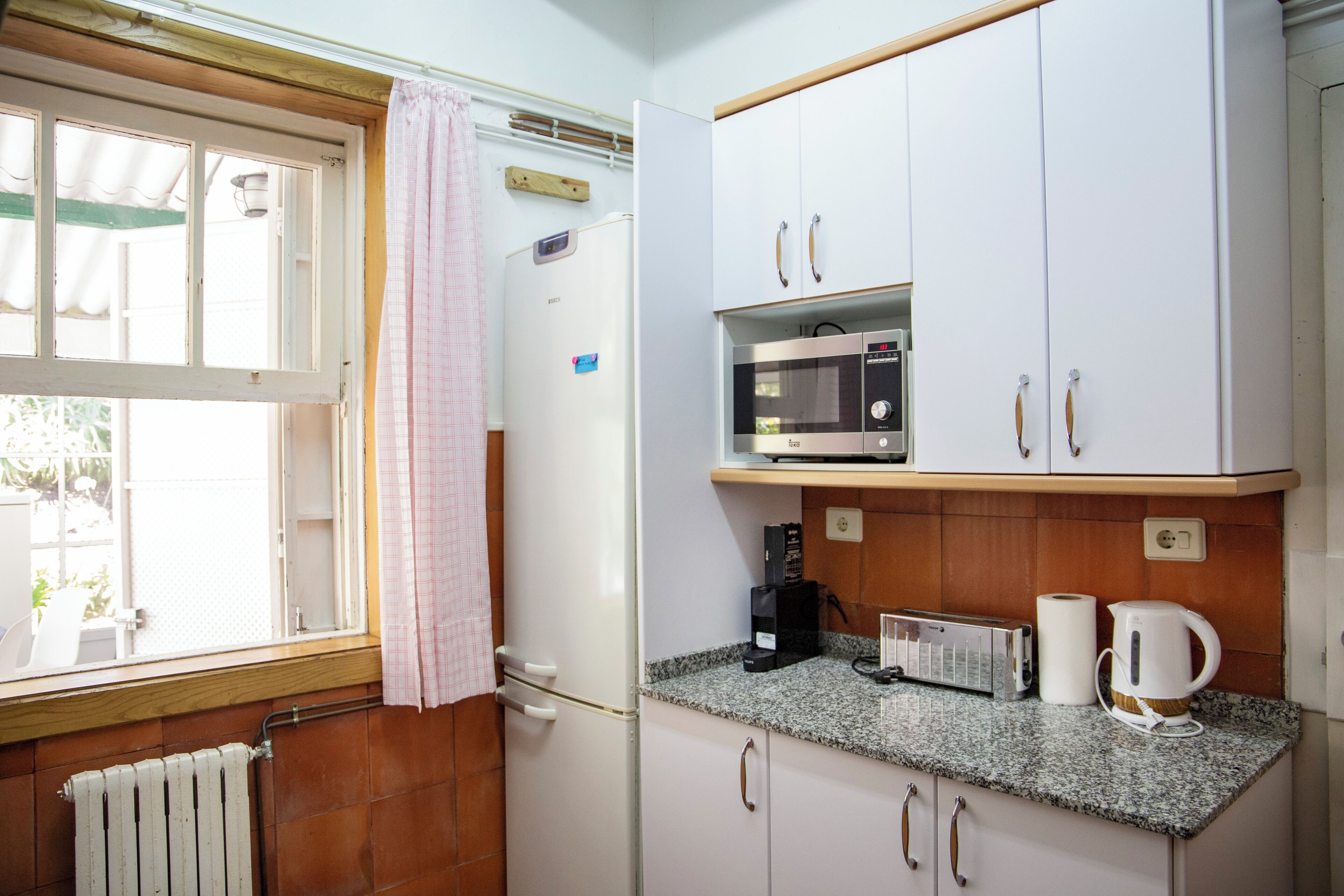 Una cucina con mobili bianchi, un forno a microonde, un tostapane e un bollitore.