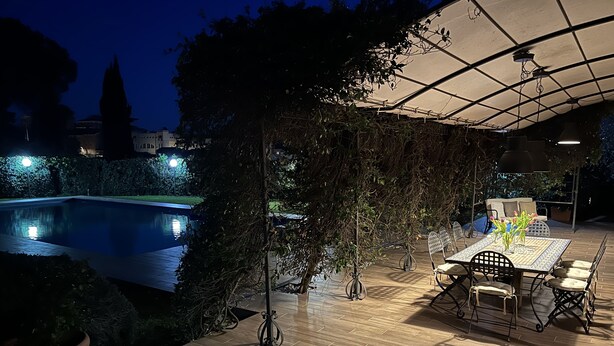 Un área de patio al aire libre con piscina, suelo de madera y una mesa con sillas.