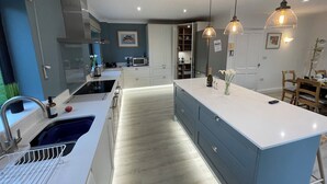 A modern kitchen with a central island, built-in appliances, and pendant lighting. - Great House nr Polzeath on golf course ideal for families (St Minver, Near Wadebridge)