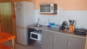 A compact kitchen with a refrigerator, microwave, sink, and a toaster oven on a shelf. - Caribgites, the Butterfly studio (Sainte-Anne)