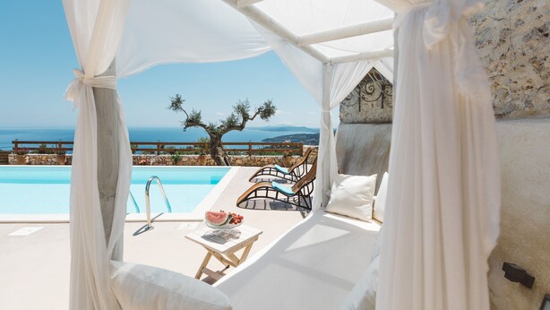 A private pool area with a canopy, lounge chairs, and a table with a watermelon and fruit.