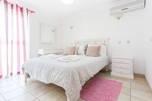 A bedroom with a bed, bedside tables, a mirror, and a window with curtains.