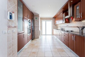 A modern kitchen with stainless steel appliances, wooden cabinets, and a tiled backsplash.