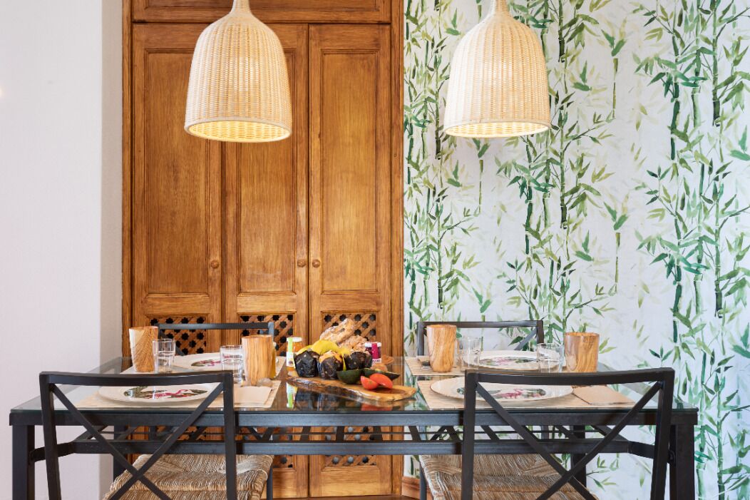 A dining table with a wooden cabinet and two hanging wicker lamps.