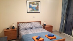 Un dormitorio con una cama, dos mesitas de noche, un escritorio y una silla.