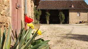 Un edificio de piedra con una puerta roja y un patio de grava.