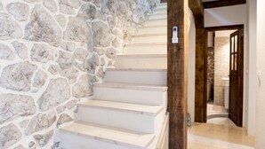 Un escalier aux marches blanches menant à un mur de pierre.