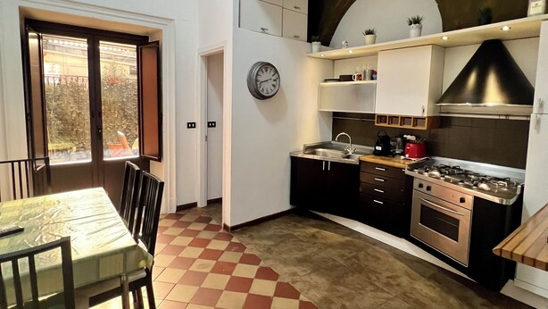 A kitchen with a checkered floor, a dining table with chairs, a clock, and a stove.