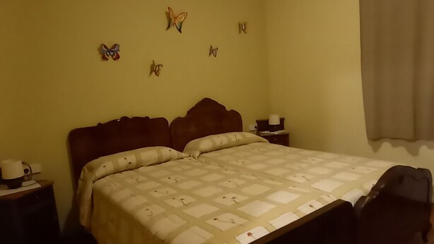Ein Schlafzimmer mit einem Bett, Nachttischen und dekorativen Schmetterlingen an der Wand.