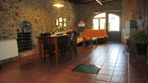 Un coin repas rustique avec un mur en pierre, une table en bois, des chaises et un sol carrelé.