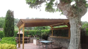Un patio couvert avec une table et des chaises, un banc et des plantes en pot.