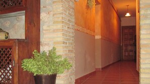 Un couloir avec un mur en briques, une porte en bois et une plante en pot.