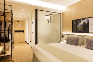 A hotel room with a bed, a wardrobe, a mirror, and a shower.