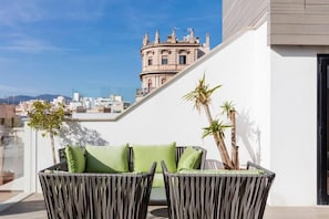 Un balcón con mobiliario de mimbre y vista a un edificio histórico.