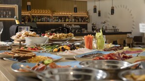 A buffet with various dishes, a bar area with bottles, and a clock on the wall.