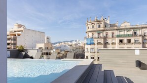 A rooftop pool with a view of a cityscape, including a historic building with balconies.
