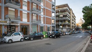 A street with multi-story buildings, parked cars, and a visible trash bin. - House Gregorio, large and comfortable apartment (Roma)