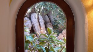 A window with a view of large rocks and green foliage. - Enchanting Country Villa in a Lush Valley with Animals, Pool, Outdoor Jacuzzi  (Rena Majore)