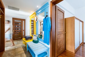 A room with a bench, a suitcase, and a mirror with a blue frame.