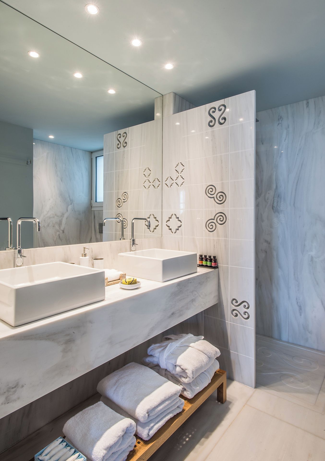 A modern bathroom with two sinks, a large mirror, and a shower area.