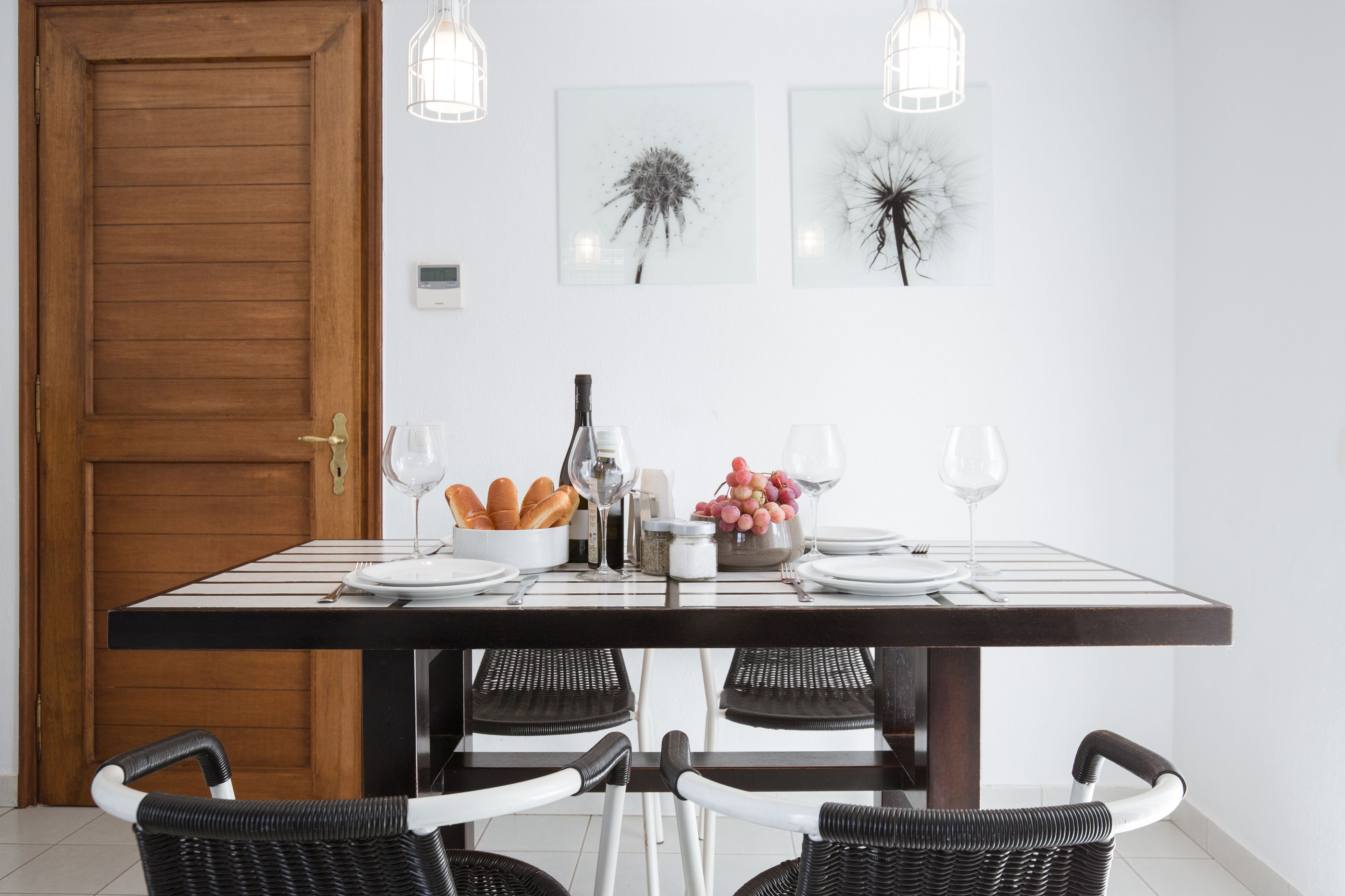 Un coin repas avec une table en bois, deux chaises, une bouteille de vin, des verres et un panier de pain.