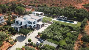 Een modern huis met een zwembad, omgeven door weelderige begroeiing en een verzorgd gazon.