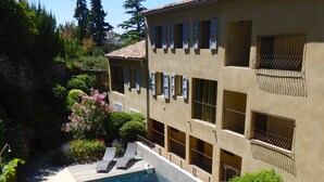 A poolside area with a clear blue pool, a stone pathway, and a building with multiple balconies and windows. - ALL COMFORT, modern, NICE TERRACE, BEAUTIFUL VIEW of MONT VENTOUX (Bonnieux)