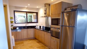A modern kitchen with stainless steel appliances, wooden cabinets, and a tiled floor. - ALL COMFORT, modern, NICE TERRACE, BEAUTIFUL VIEW of MONT VENTOUX (Bonnieux)