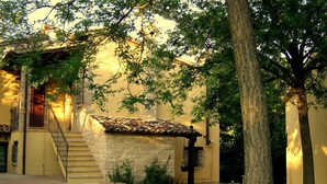 Um edifício com fachada de pedra, telhado em telhas e escadaria que leva à entrada.