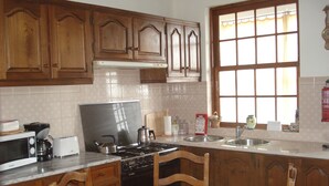 A kitchen with wooden cabinets, a stove, a microwave, and a dining table with chairs.