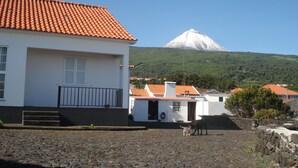 A white building with a red-tiled roof, a stone wall, and a cobblestone ground.