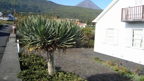A building with a white exterior, a balcony with a metal railing, and a mountain in the background.