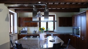 Una cocina con una isla grande, armarios de madera oscura, electrodomésticos de acero inoxidable y una lámpara colgante.