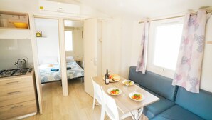 A compact living space with a kitchenette, a dining area, and a sofa. - Happy Camp in Camping Bella Sardinia (Cuglieri)