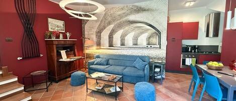 Una sala de estar con chimenea, un sofá, una mesa de centro y un comedor con sillas.