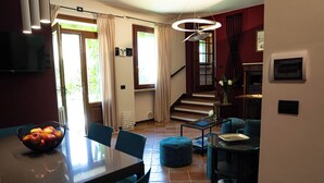 A dining area with a table, chairs, a bowl of fruit, and a staircase leading to an upper level.