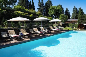 A swimming pool with lounge chairs and umbrellas, surrounded by greenery and trees. - Luxury apartment with pool: dolce vita at 15' on foot from the heart of Siena! (Siena)