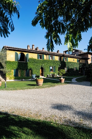 A building with a yellow facade, green shutters, and a gravel driveway.