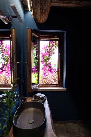 A bathroom with a window, a sink, and a mirror.