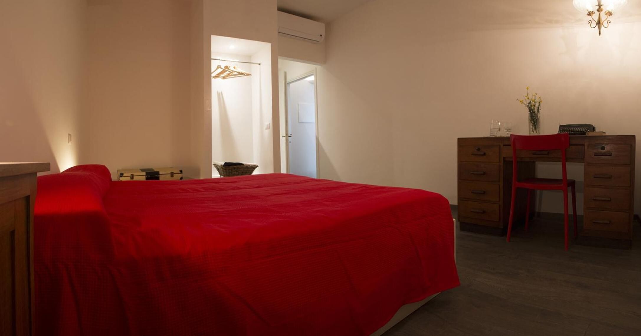 A bedroom with a bed, a desk, a chair, and a dresser.