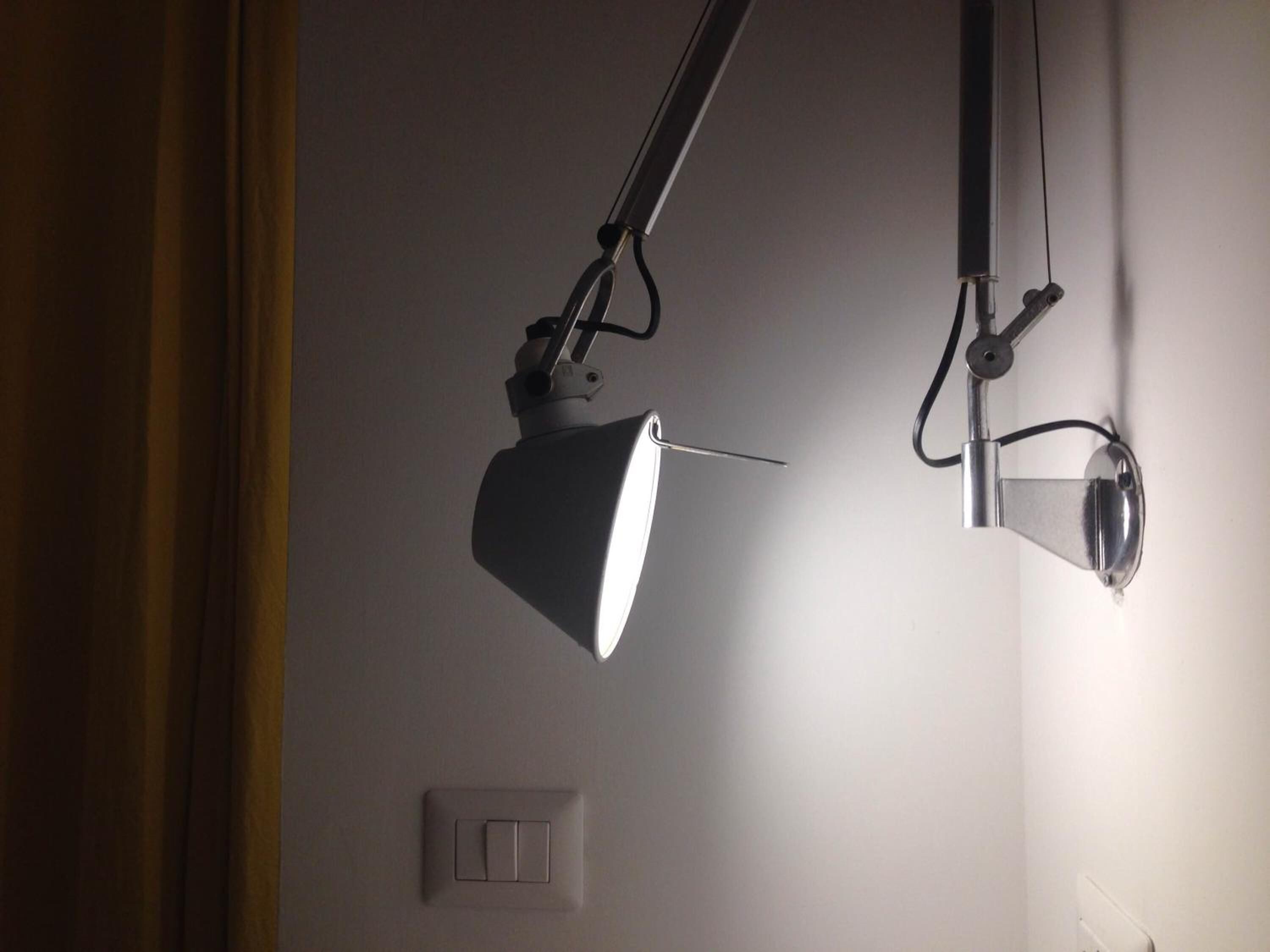 Two adjustable desk lamps mounted on a white wall, with a light switch visible below them.