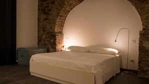 A bedroom with a large bed, a stone wall, and a modern lamp. - Residenza la Corte Assisi (Assisi)