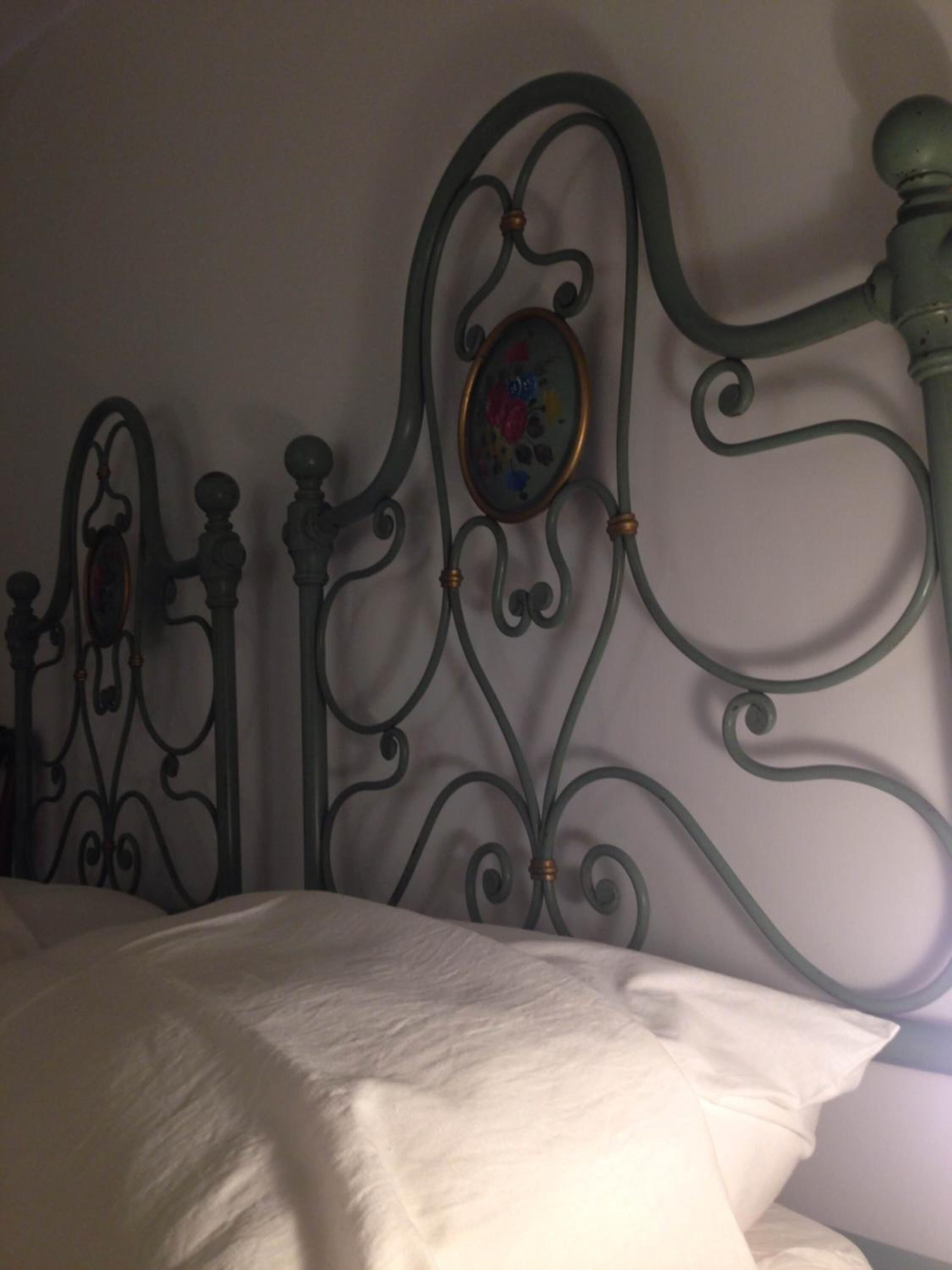 A bed with a metal headboard featuring decorative elements and a framed picture.
