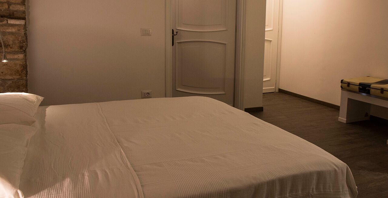 A bedroom with a bed, a door, and a bench.