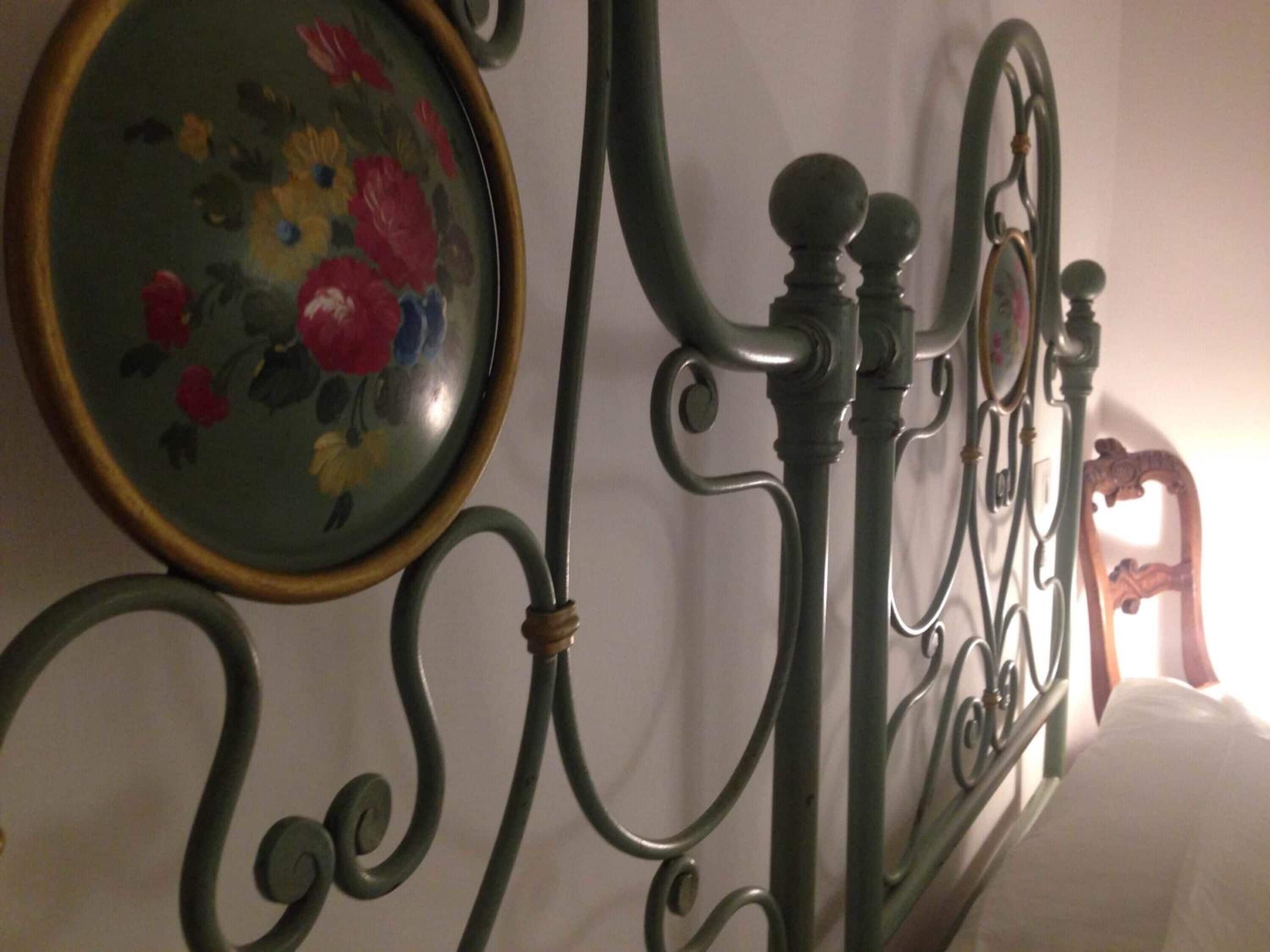 A metal bed frame with ornate designs and a floral-patterned mirror.