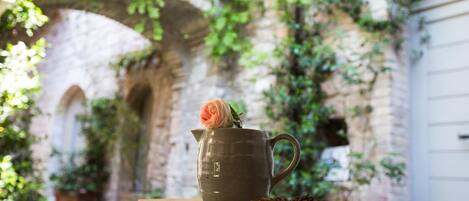 A rustic setting with a wooden table, a ceramic pitcher with a rose, and a pine cone.