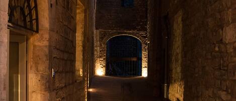 A narrow stone corridor with a door at the end, illuminated by a single light source.
