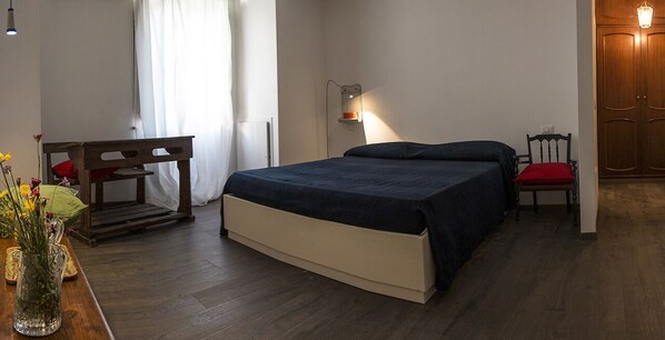 Un dormitorio con cama, mesita de noche, silla y lámpara.